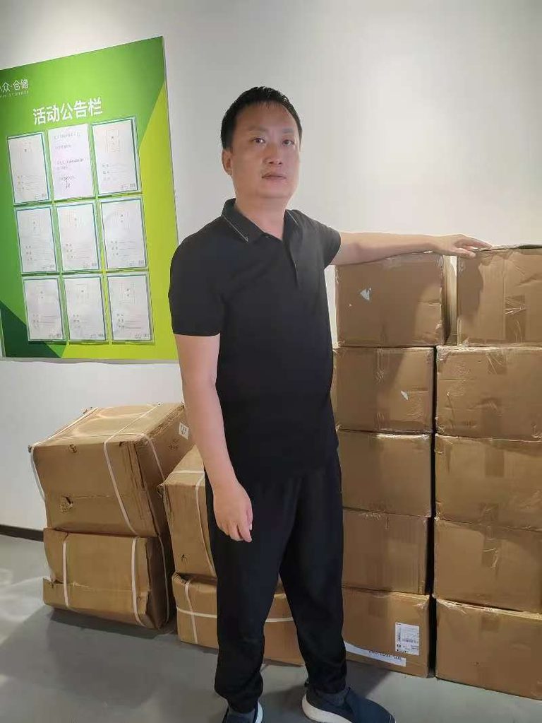 Zhiwei Yan standing next to consolidated cartons for an SME client in the Shenzhen warehouse