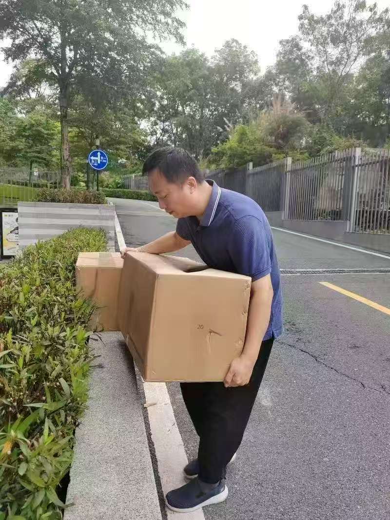 Zhiwei Yan carrying heavy cartons for order consolidation outside the Shenzhen warehouse.